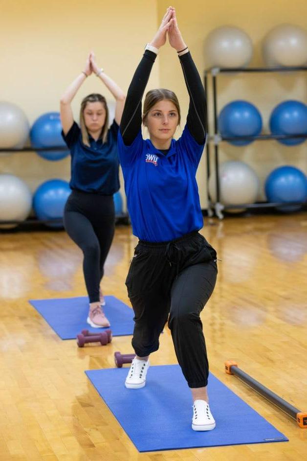 澳门新普京注册 students in a yoga class holding a yoga pose